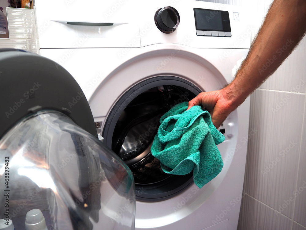 A man puts dirty laundry into a washing machine. Cleanliness in the house. Big washing. A man puts dirty laundry into a washing machine. Cleanliness in the house. Big washing.