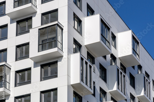 Compact balconies on the white facade of the condominium. Multi-storey apartments. Small living space