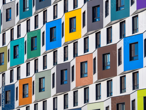 The multi-colored facade of a high-rise residential building. Rows of windows photo
