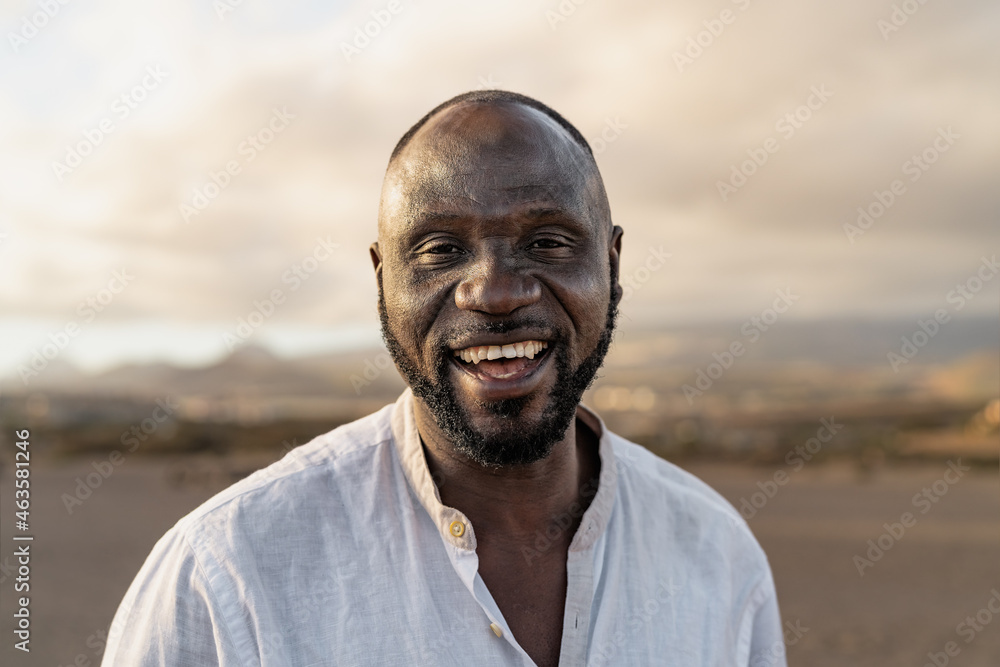 Happy African man smiling in camera on the beach during summer vacation Happy African man smiling in camera on the beach during summer vacation