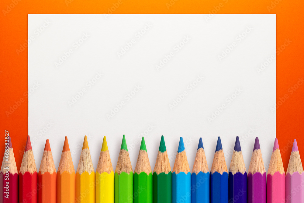 Frame made of color pencils and white paper on an orange background. Frame made of color pencils and white paper on an orange background.