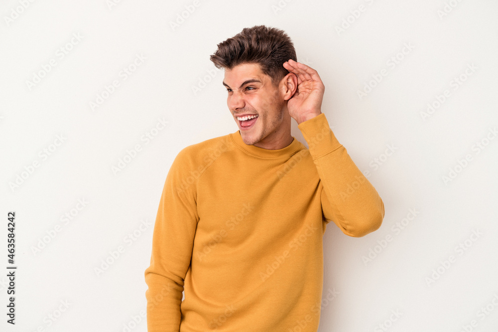 Young caucasian man isolated on white background trying to listening a gossip. Young caucasian man isolated on white background trying to listening a gossip.
