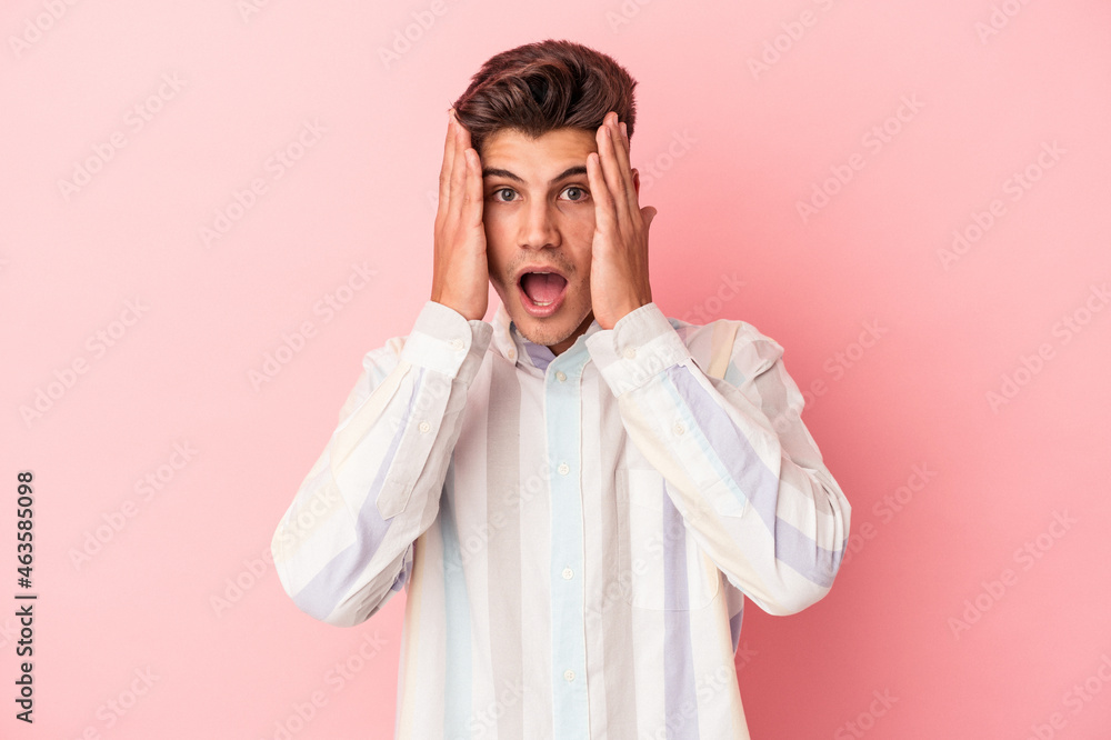 Young caucasian man isolated on pink background having fun covering half of face with palm. Young caucasian man isolated on pink background having fun covering half of face with palm.
