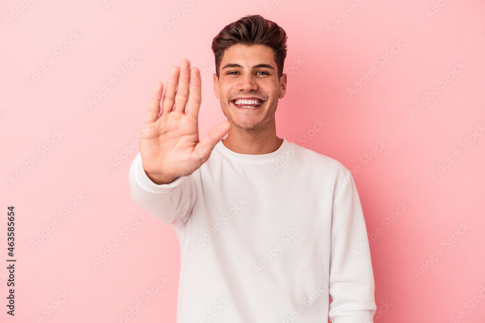 Young caucasian man isolated on pink background smiling cheerful showing number five with fingers. Young caucasian man isolated on pink background smiling cheerful showing number five with fingers.