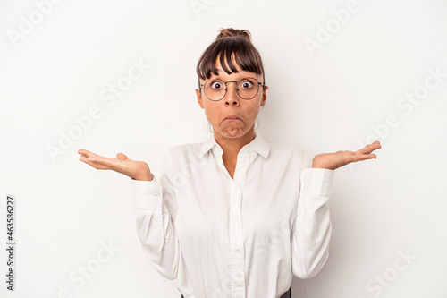 Young mixed race business woman isolated on white background shrugs shoulders and open eyes confused.