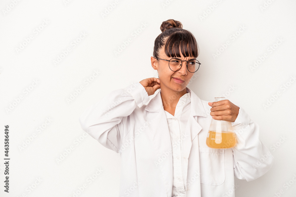 Young mixed race scientist woman holding a test tube isolated on white background touching back of head, thinking and making a choice. Young mixed race scientist woman holding a test tube isolated on white background touching back of head, thinking and making a choice.