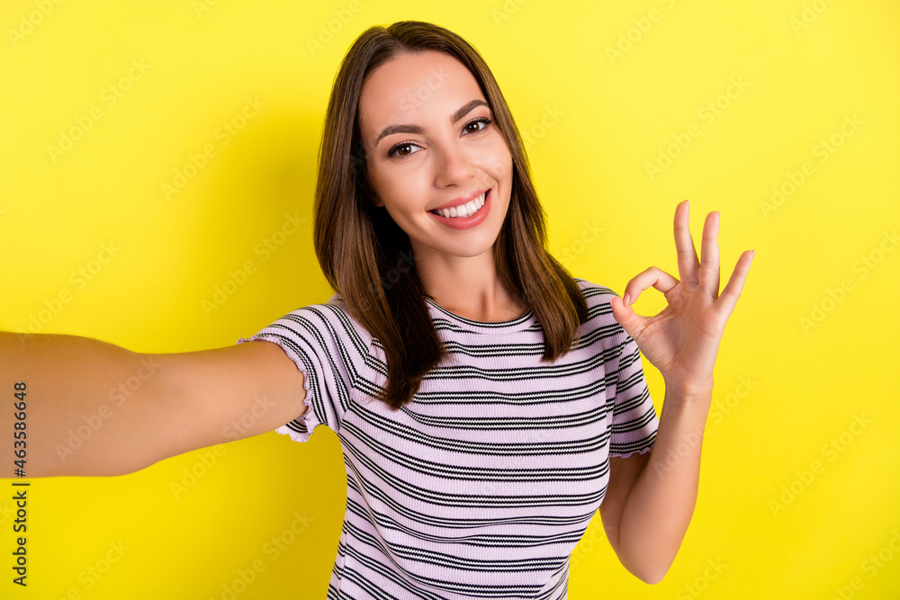 Photo of sweet millennial brunette lady do selfie show okey wear white t-shirt isolated on yellow background Photo of sweet millennial brunette lady do selfie show okey wear white t-shirt isolated on yellow background