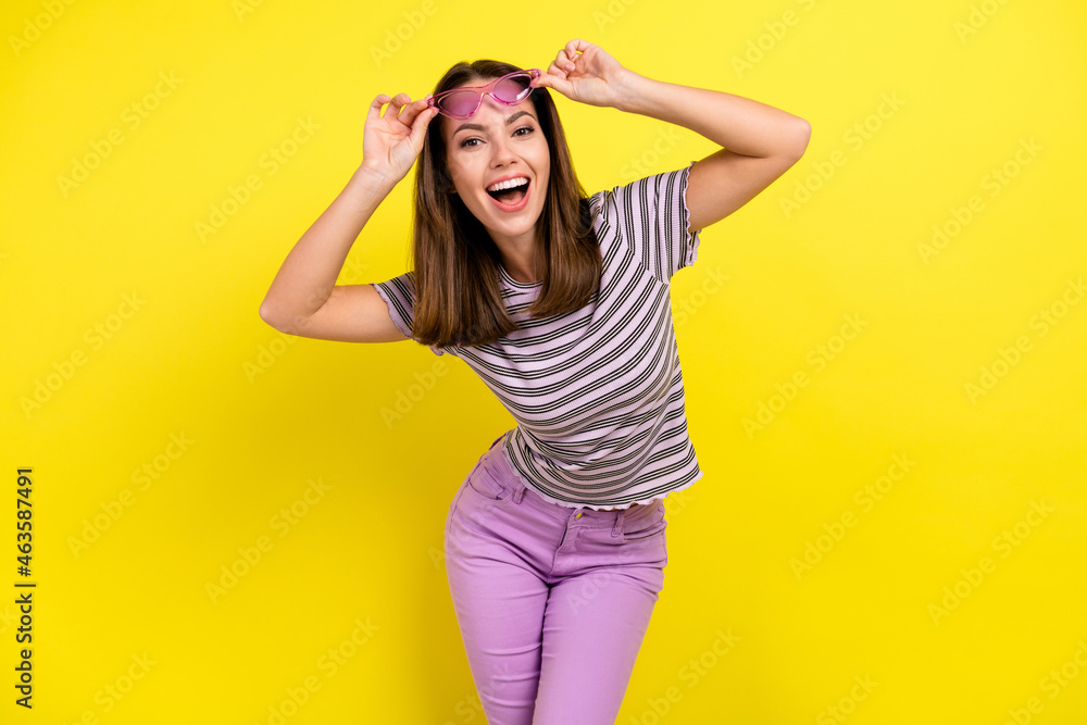 Photo of impressed young brunette lady wear eyewear t-shirt isolated on yellow background Photo of impressed young brunette lady wear eyewear t-shirt isolated on yellow background