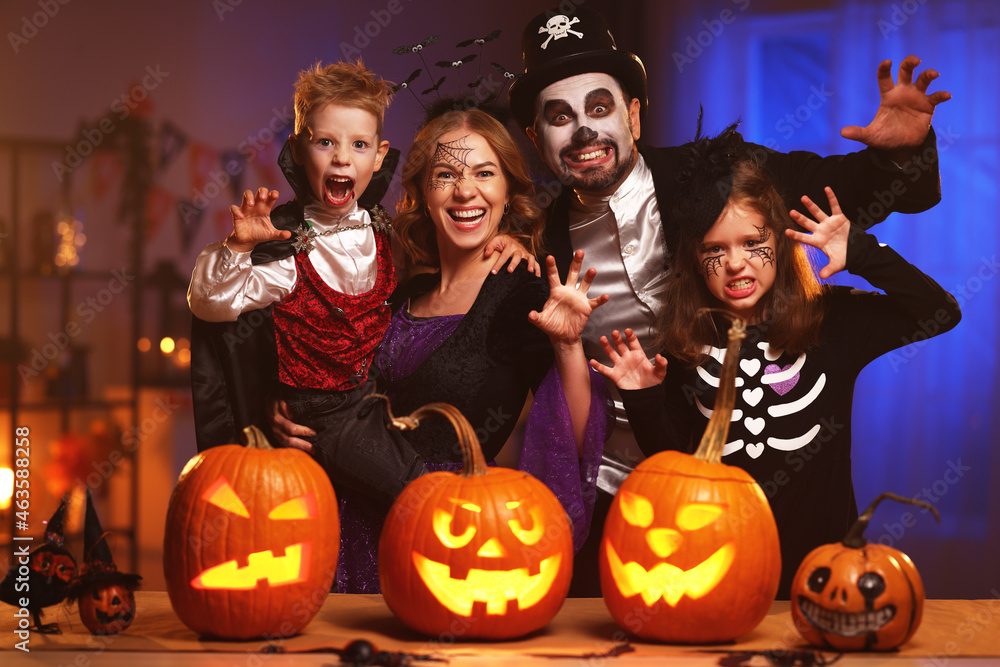 Young caucasian family mother father and children in Halloween costumes and makeup making scary gesture, saying trick or treat while celebrating together all hallows eve in dark room at home - obrazy, fototapety, plakaty 