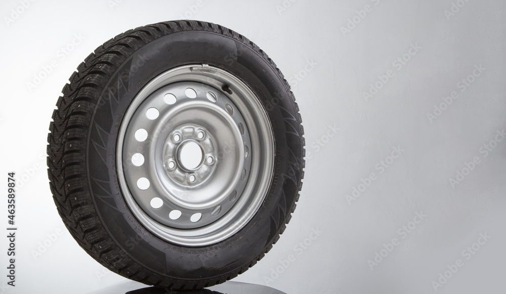 Car wheel and winter studded tire on grey background Car wheel and winter studded tire on grey background