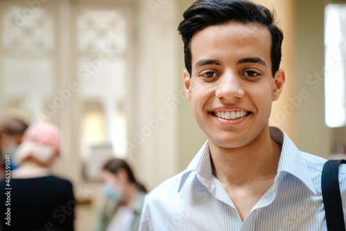 Young middle eastern man smiling at camera while standing indoors
