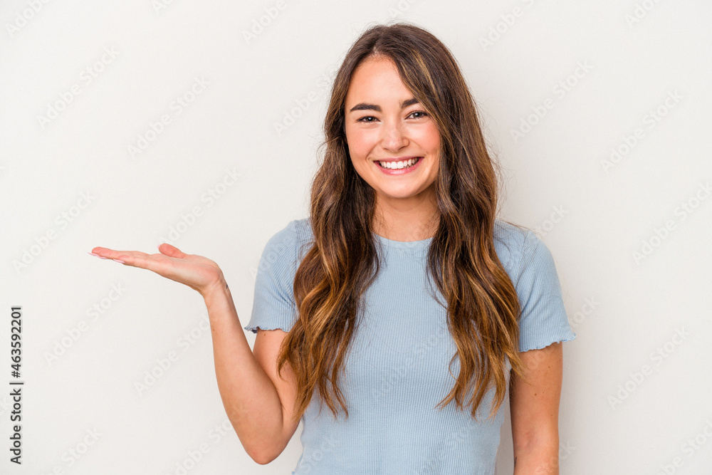 Young caucasian woman isolated on white background showing a copy space on a palm and holding another hand on waist. Young caucasian woman isolated on white background showing a copy space on a palm and holding another hand on waist.