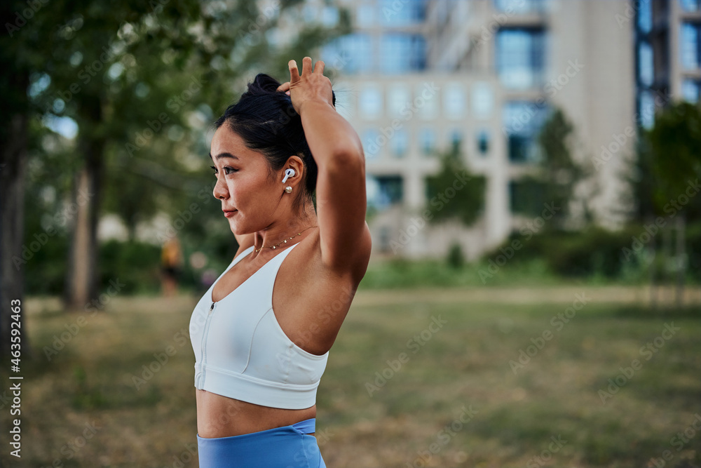 Sportswoman tying her hair before running outdoors Sportswoman tying her hair before running outdoors