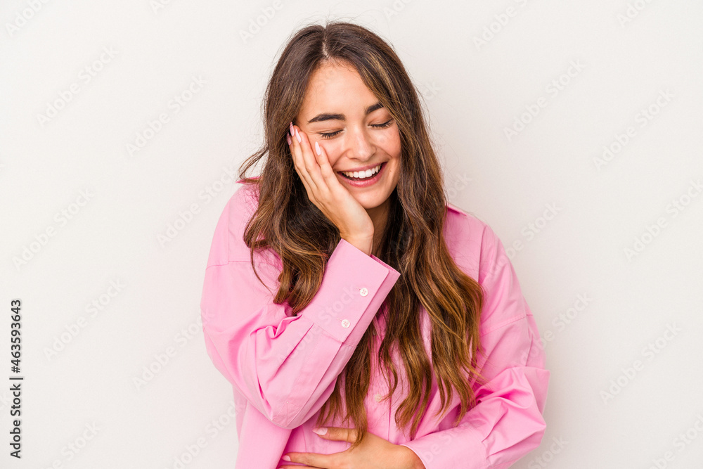 Young caucasian woman isolated on white background laughs happily and has fun keeping hands on stomach.
