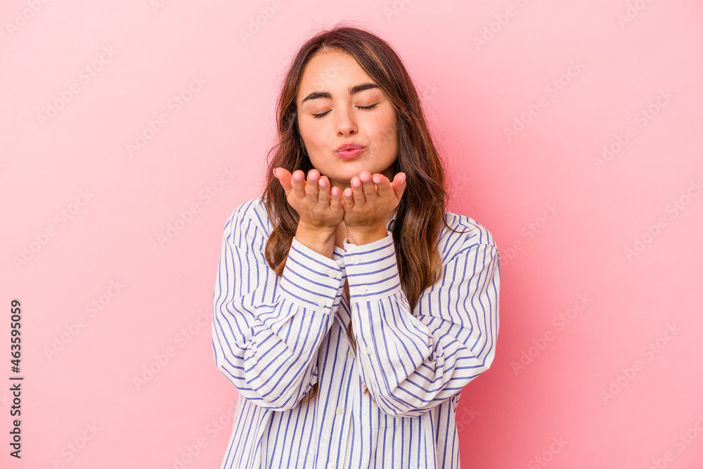 Young caucasian woman isolated on pink background folding lips and holding palms to send air kiss. Young caucasian woman isolated on pink background folding lips and holding palms to send air kiss.