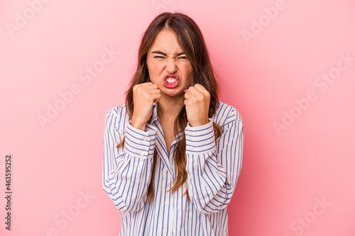 Young caucasian woman isolated on pink background showing fist to camera, aggressive facial expression.