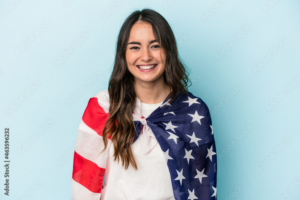 Young caucasian woman holding an American flag isolated on blue background happy, smiling and cheerful. Young caucasian woman holding an American flag isolated on blue background happy, smiling and cheerful.