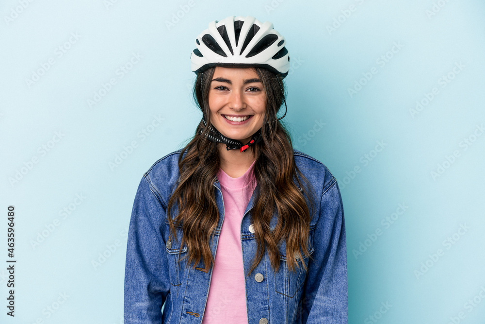 Young caucasian woman rinding a bike isolated on blue background happy, smiling and cheerful. Young caucasian woman rinding a bike isolated on blue background happy, smiling and cheerful.