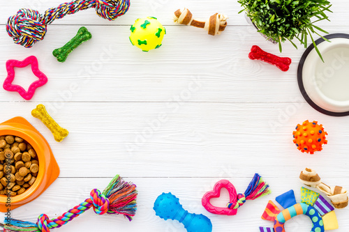 Dry dog food in bowl with toys and treats, top view photo