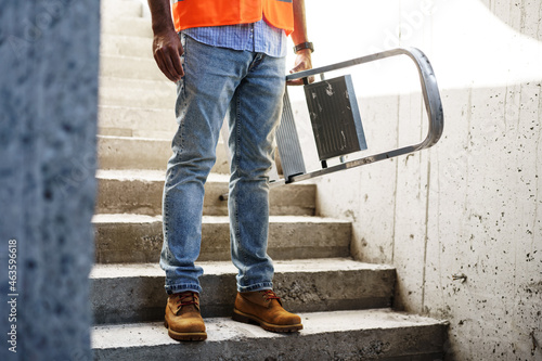 Professional builder carrying metal ladder, close up