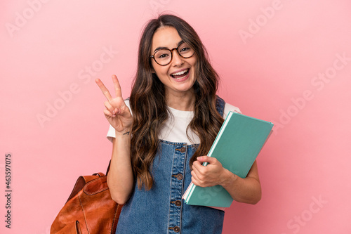 Картината върху платно Young caucasian student woman isolated on pink background joyful and carefree showing a peace symbol with fingers