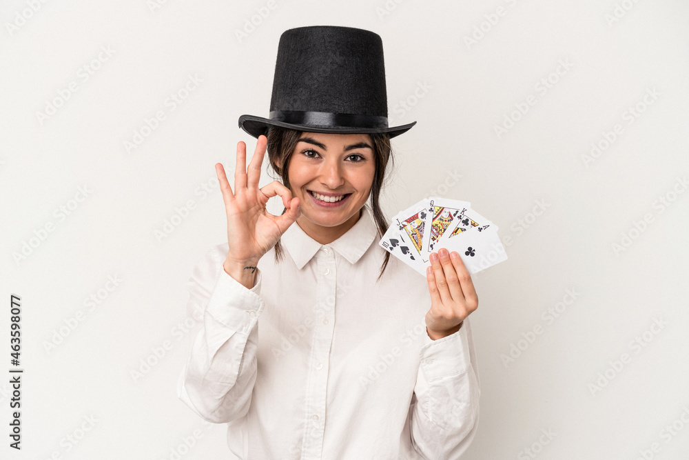 Young magician woman holding a wand isolated on white background cheerful and confident showing ok gesture. Young magician woman holding a wand isolated on white background cheerful and confident showing ok gesture.