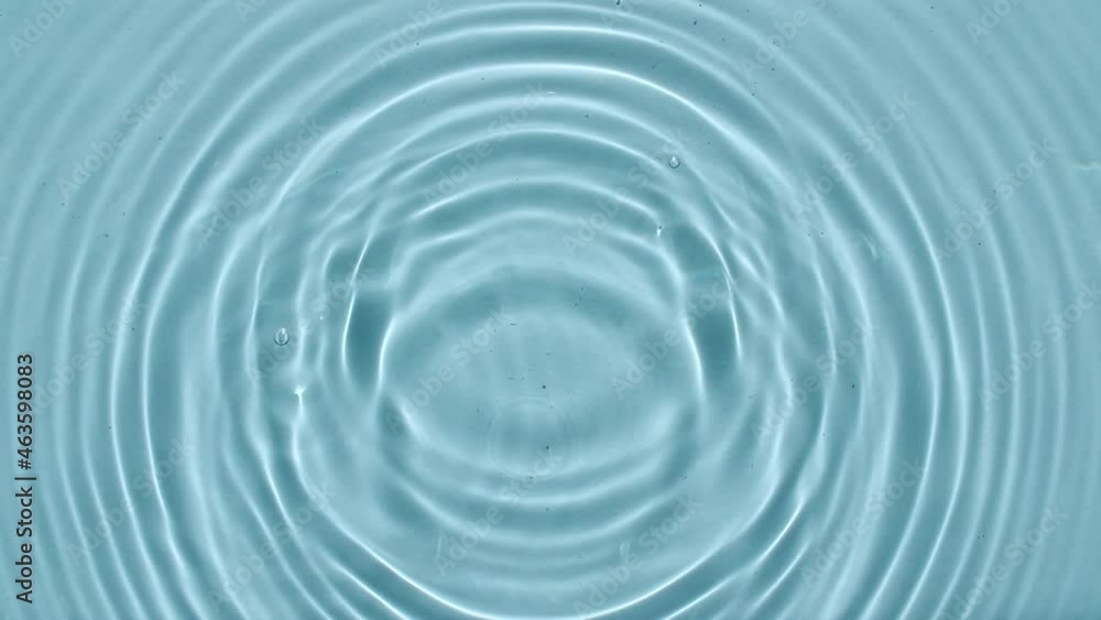 Top view slow motion of drop falls into water and diverging circles of water on blue background. Water drop splash blue colored. Sun and shadows. 4k. High quality 4k footage Top view slow motion of drop falls into water and diverging circles of water on blue background. Water drop splash blue colored. Sun and shadows. 4k. High quality 4k footage
