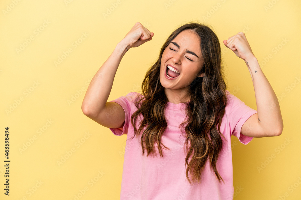 Fototapeta premium Young caucasian woman isolated on yellow background raising fist after a victory, winner concept.