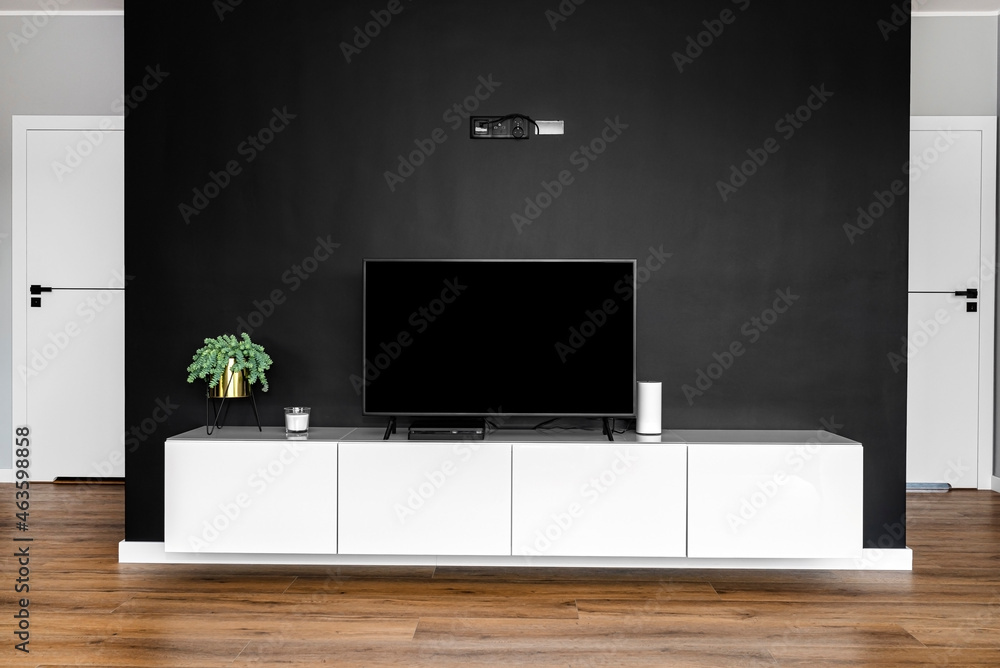 Black matte TV wall in the living room with a standing TV set on a white  hanging cabinet. foto de Stock | Adobe Stock