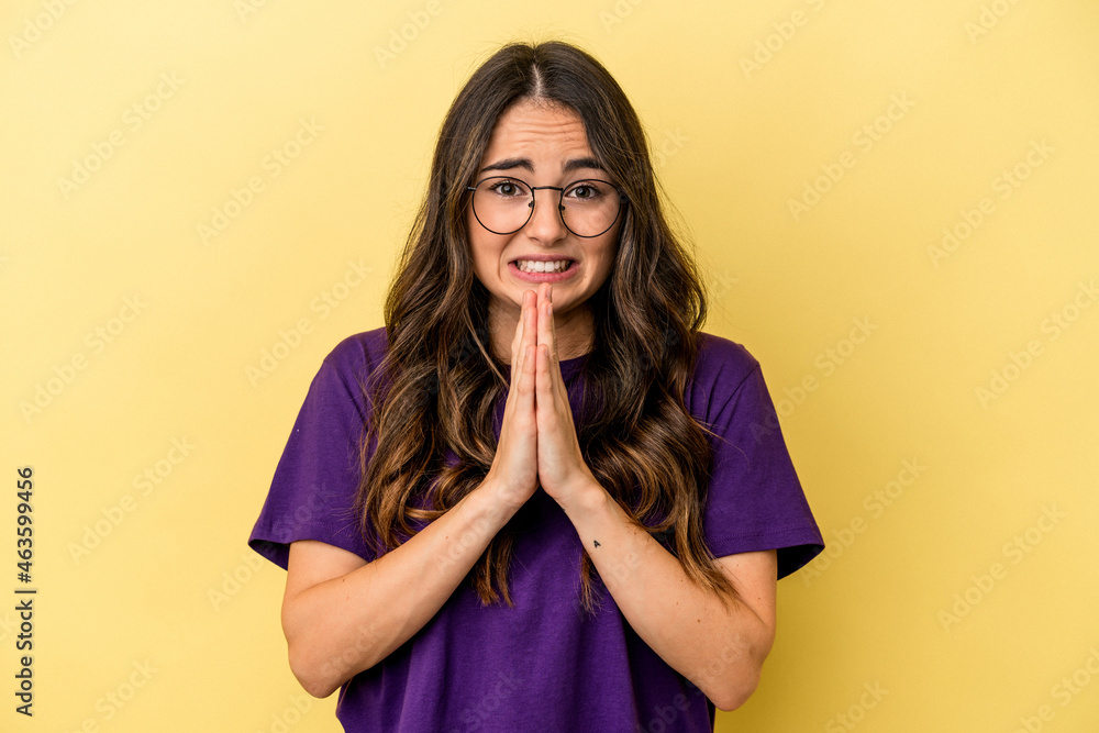 Young caucasian woman isolated on yellow background holding hands in pray near mouth, feels confident. Young caucasian woman isolated on yellow background holding hands in pray near mouth, feels confident.