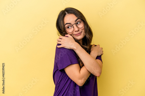 Young caucasian woman isolated on yellow background hugs, smiling carefree and happy.