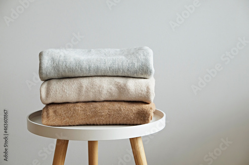 Bunch of knitted warm pastel color sweaters with different knitting patterns folded in stack, clearly visible texture. Stylish fall-winter season knitwear clothing. Close up, copy space for text. photo