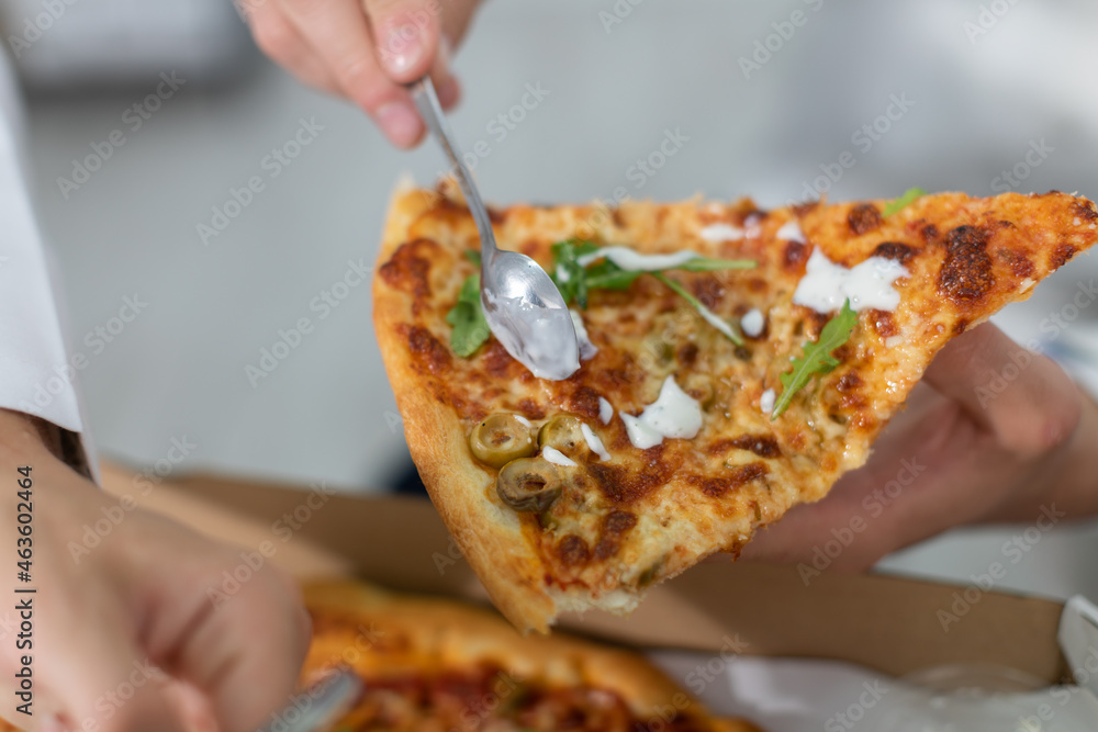 During a break, a doctor spreads sauce on a pizza to eat it.