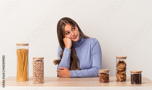 Young caucasian woman sitting at a table with food pot isolated on white background who feels sad and pensive, looking at copy space.