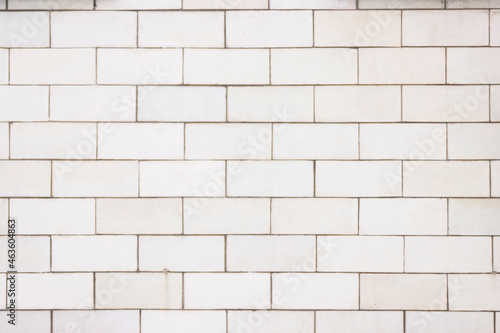 The wall is lined with light beige tiles. Geometric rectangular texture.