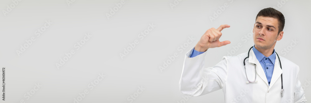 A doctor holds a blank space in two fingers to promote a new product. Panoramic view. A doctor holds a blank space in two fingers to promote a new product. Panoramic view.