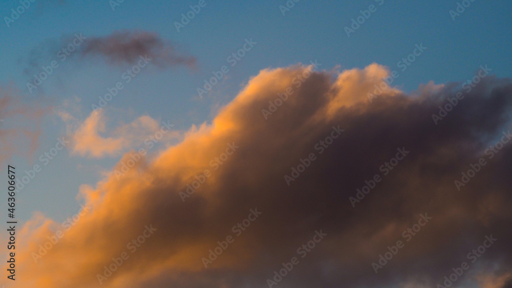Zoom sur un cumulus illuminé par une lumière orangée, pendant le coucher du soleil