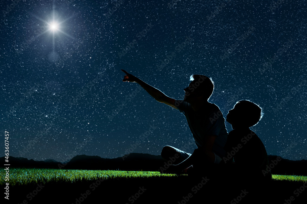 Fototapeta premium dad and son sit on the grass at night and look at the night sky