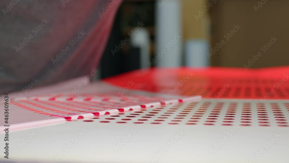 An employee peels off the excess film from plotted round stickers. An employee peels off the excess film from plotted round stickers.