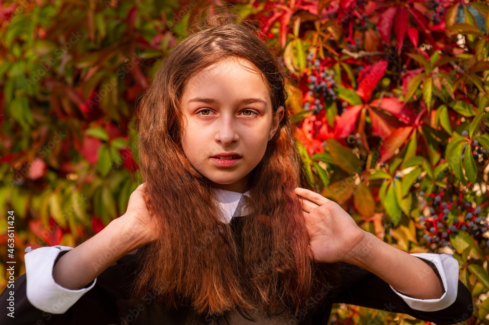 A girl straightens her curly hair in nature. Schoolgirl portrait. A girl straightens her curly hair in nature. Schoolgirl portrait.