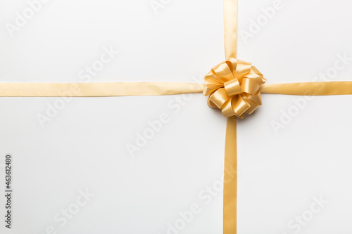 Top view of gold ribbon rolled and yellowbow isolated on colored background. Flat lay with copy space photo