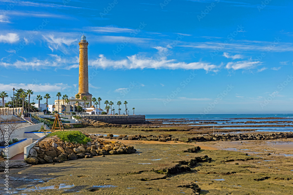 Fototapeta premium lighthouse on the beach in Chipiona during low tide on the shore are old fishing corrals