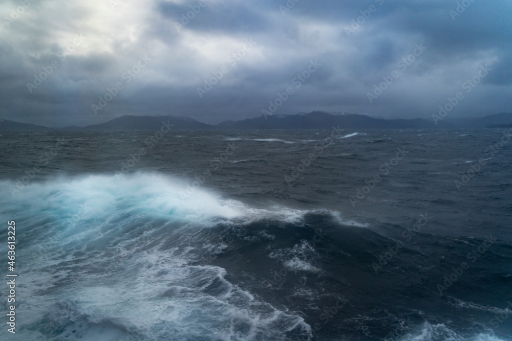 Wellen auf der Reise mit dem Schiff zum Nordkap, Norwegen. Sturm auf dem Atlantik mit Schaumkronen auf den Wellen und Gischt auf dem Schiff. dunkle Wolken werden vom Wind über das Meer gejagt. Ozean