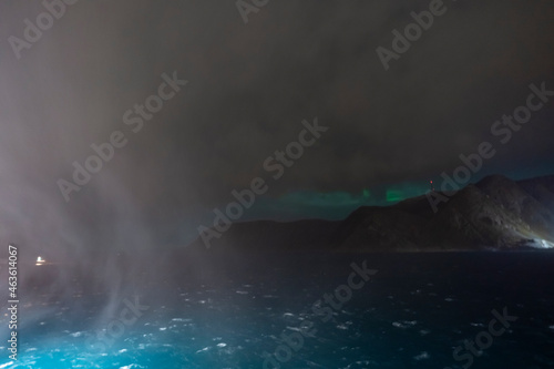 Nordlichter in Honningsvåg, Norwegen. Aurora borealis über dem Berg und Schneegestöber im Vordergrund. die Dame tanzt am Himmel. Aurora schwaches Licht in der Nacht, schnell wechselndes Wetter photo