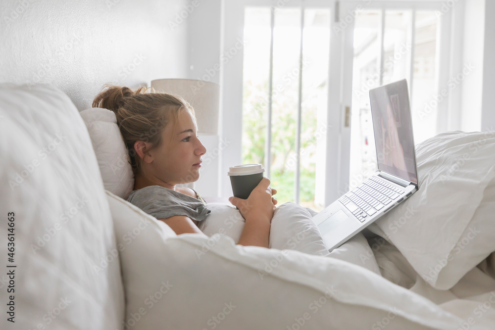 teenage girl lying in bed using laptop teenage girl lying in bed using laptop