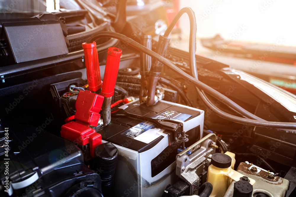 car repair concept. closeup charging car battery with electricity through jumper cables with soft-focus and over light in the background - obrazy, fototapety, plakaty 