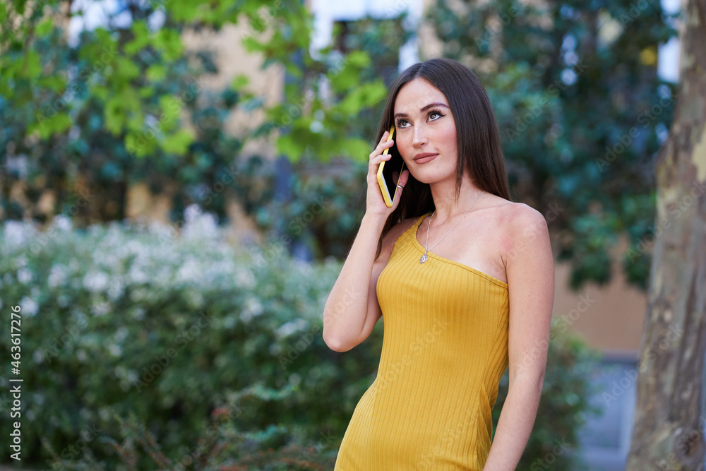 young woman talking on the smartphone in a garden area looking up young woman talking on the smartphone in a garden area looking up