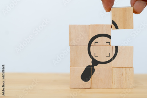 Identify and clarify concept. Market and customer target and focusing. Hand hold the wooden cubes with magnifying glass and cropped object symbols on white background with copy space.