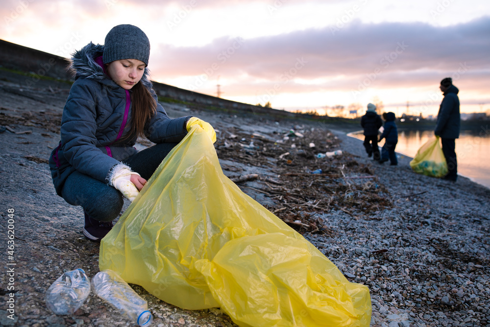 Preteen girl cleaning polluted sea shore from plastic garbage with her ...