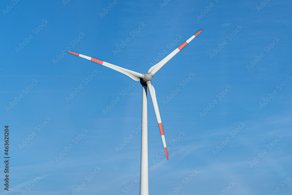 Wind turbine with three arms for electricity production standing in West Germany with a blue sky background. Wind turbine with three arms for electricity production standing in West Germany with a blue sky background.